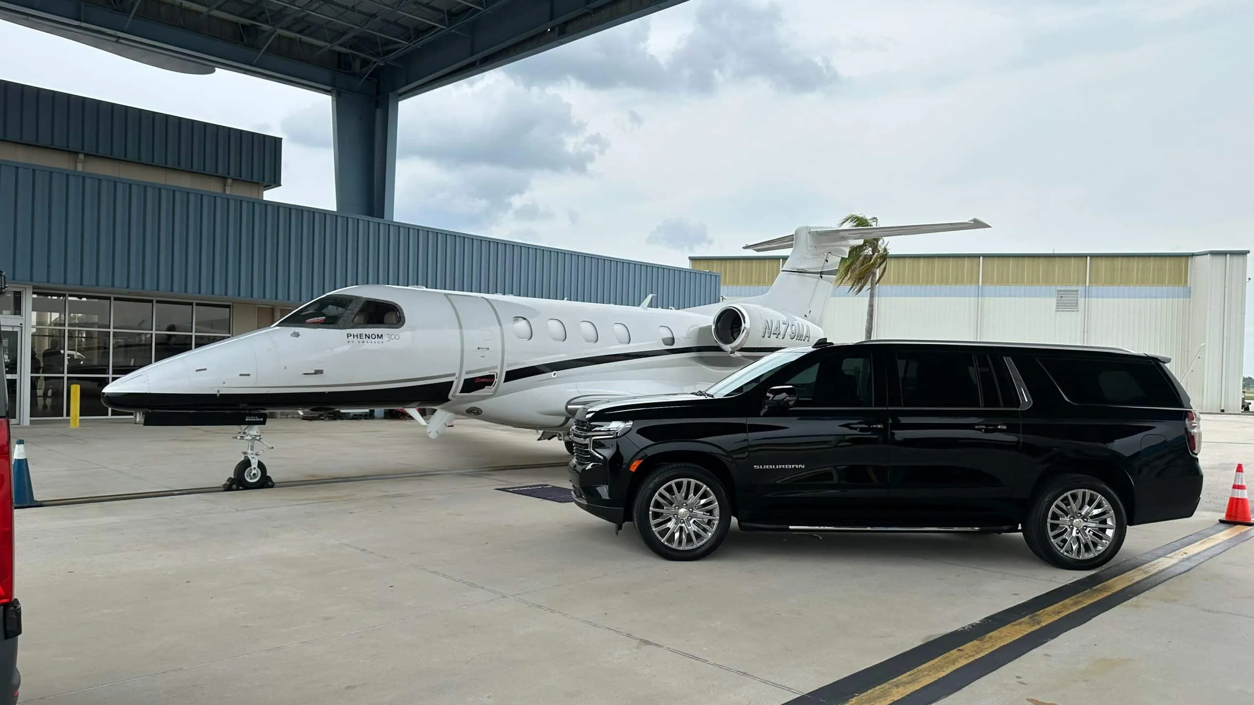 Luxury black SUV chauffeur handling luggage curbside for an Orange County airport transfer